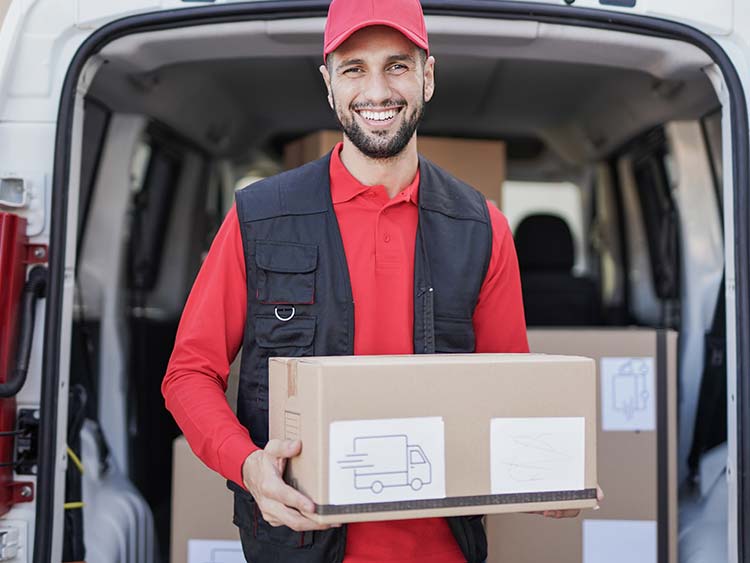 Delivery driver holding a box standing beside open truck